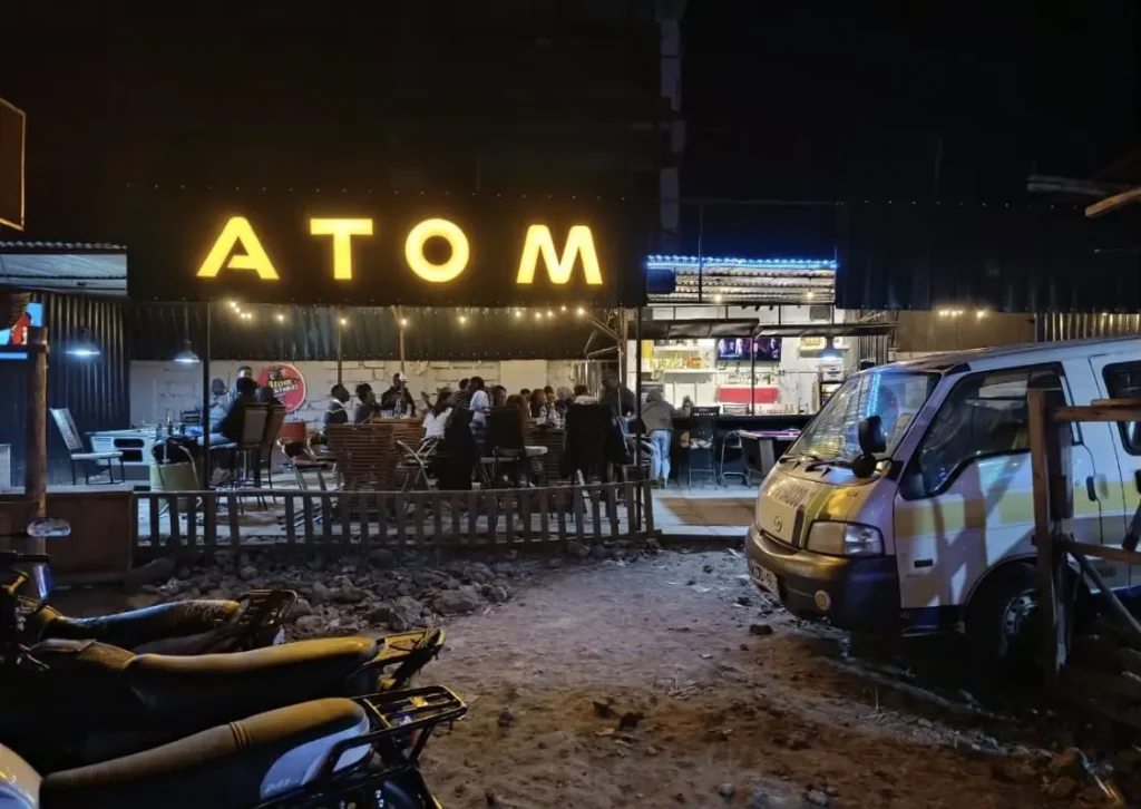 Illuminated ATOM shop sign at night